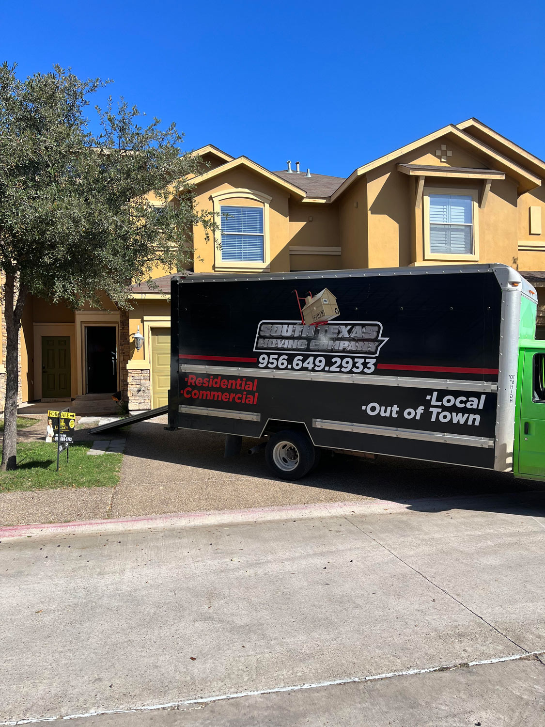 image or a yellow townhome with moving truck in driveway